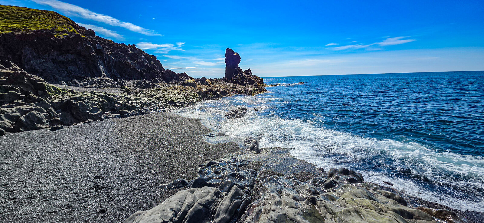 The black-pebble beach at Djúpalónssandur with waves and a sea stack offshore