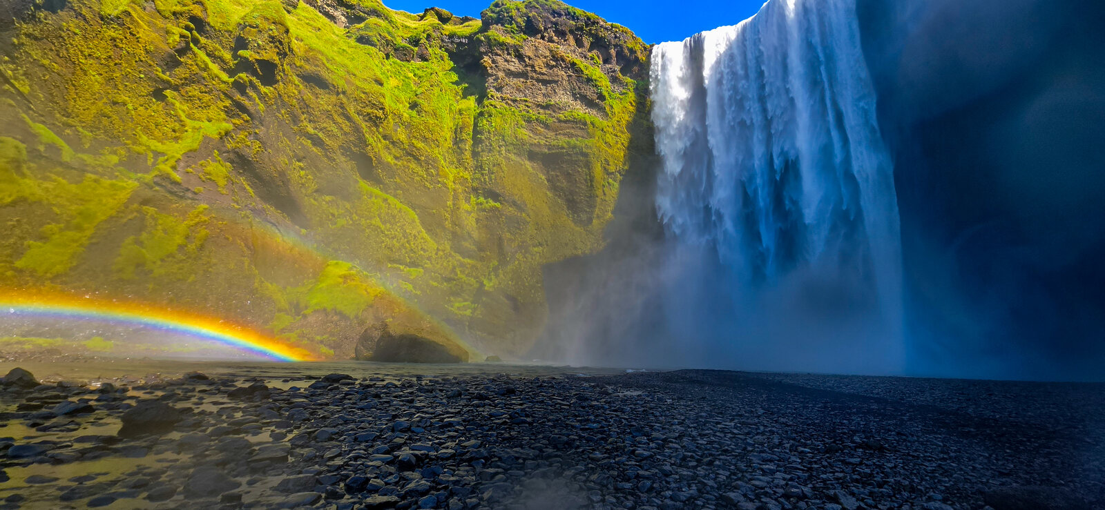 Skógafoss with a rainbow arcing across the mist at its base