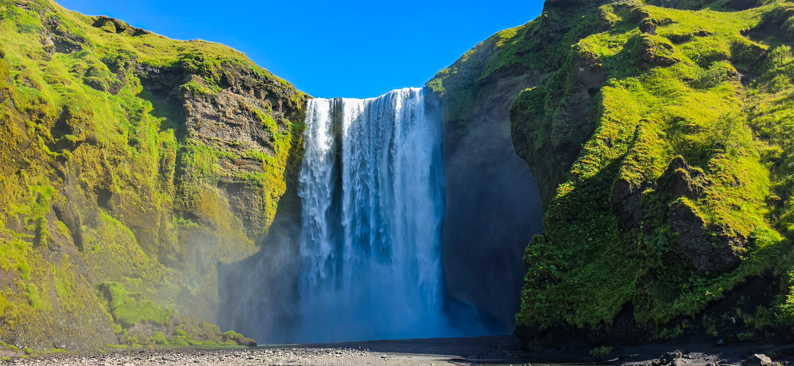 Skógafoss waterfall dropping 60 metres between vivid green cliffs
